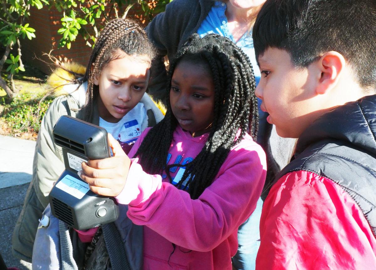 3 students look at an air quality meter