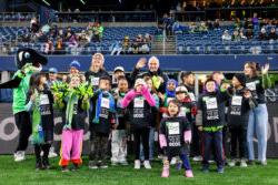在西雅图海湾足球俱乐部的比赛中，被评为“RAVE社区最佳孩子”的新星小学生们微笑着向镜头挥手.